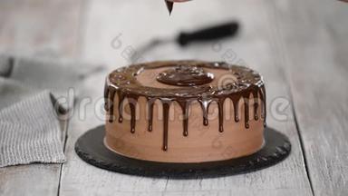 玻璃巧克力蛋糕与融化的巧克力。 女人把巧克力倒在蛋糕上。 自制可可分层蛋糕。